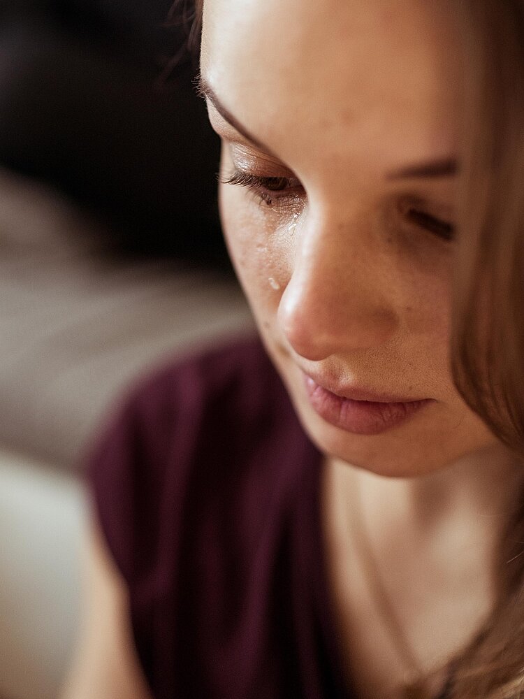 Nahaufnahme auf das Gesicht einer trauernden jungen Frau.